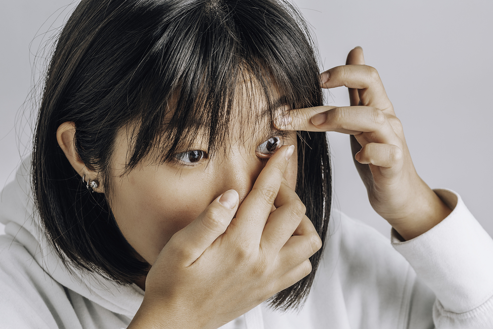 Young Asian women inserting a contact lens